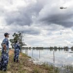 HERE TO HELP: Kade Kennaway and Anya Morris watch as a NSW Rural Fire Service helicopter delivers sandbags to the residence of Stephen and Margaret, to assist in retaining a burst water levee on their property.
