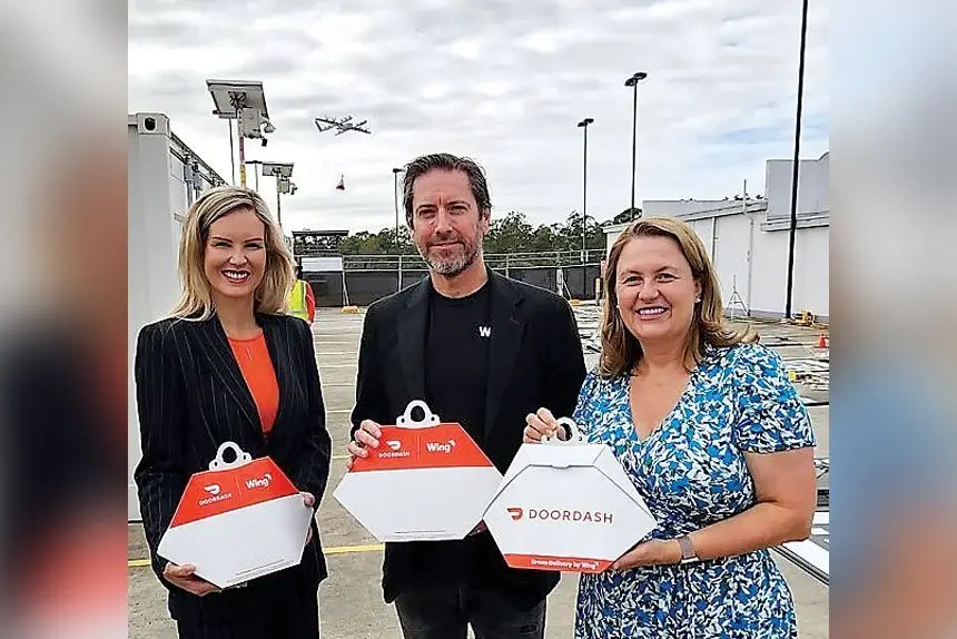 GOOD TO GO: A Wing Australia drone takes off behind Cr Nicole Jonic, Simon Rossi and Mayor Teresa Harding as it flies out to deliver one of the first food packs from the Orion Springfield drone nest.