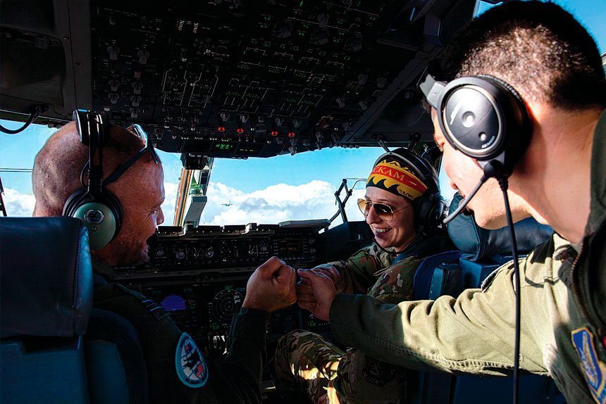 Royal Australian Air Force pilot, Squadron Leader Dirk Taylor (left), United States Air force pilots, First Lieutenant Kristen Nye (middle), Captain Joshua Torano (right) fist bump after a successful load drop from a RAAF C-17A Globemaster III aircraft.