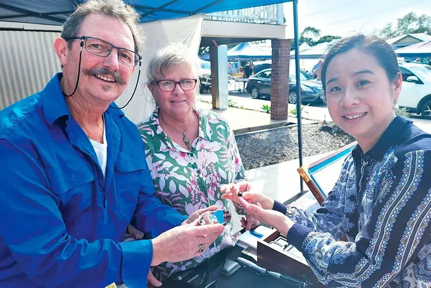 Local gem dealers, Maurie and Toni Newbery show Heather Hu one of their gems.