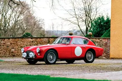This meticulously restored 1957 AC Aceca-Bristo, finished in vivid red with white racing roundels, is being auctioned through RM Sotheby’s.